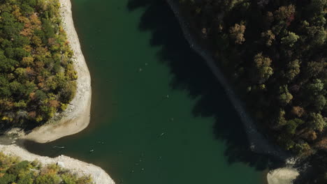 Top-view-of-Eagle-hollow-cave-river-banks-surrounded-by-dense-forest-trees