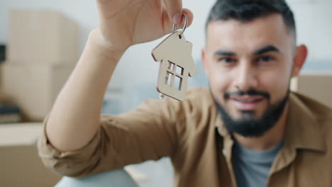 man holding wooden house shaped keychain