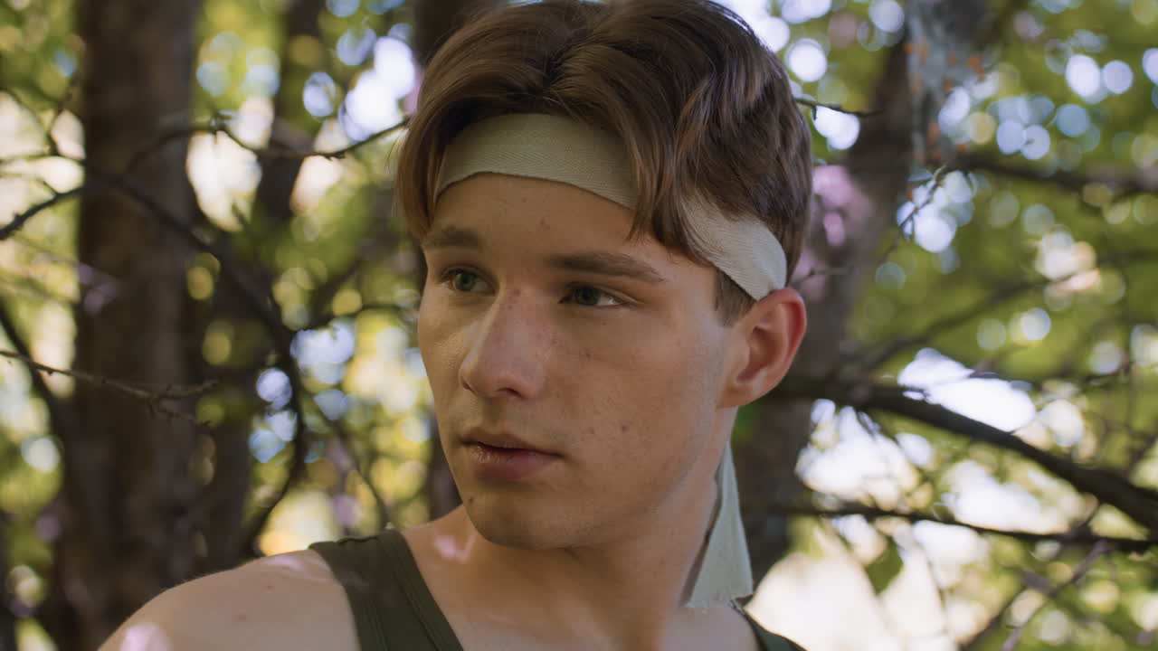 white man close up raising eyebrow while scanning forest surroundings expression curious alert sweat glistening on brow soft sunlight filtering through leafy canopy fine branches framing profile