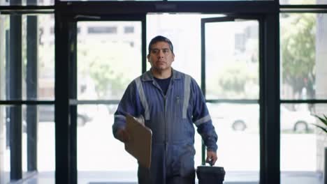 an industrious worker stands at the entrance of a building, holding a clipboard and a briefcase, reflecting on his tasks ahead with determination and focus