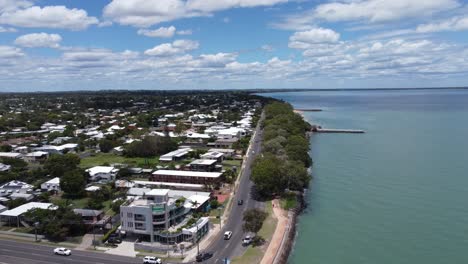 Aerial-view-of-a-coastal-road-in-a-beach-town-and-a-pier-in-the-back-ground