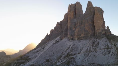 South-Tyrol-Tre-Cime-mountains-frosty-peak-aerial-reverse-view-pull-back-to-reveal-glowing-sunrise