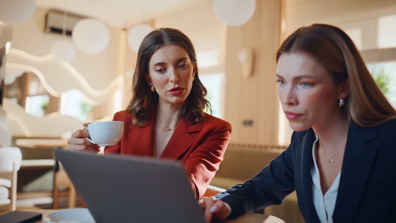 Business partners watching laptop at work meeting in cafe closeup. Two woman