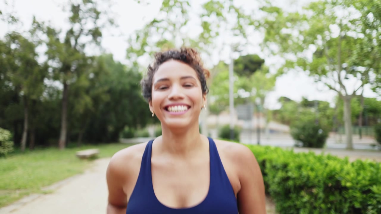 Giovane donna energica che corre e sorride in un parco