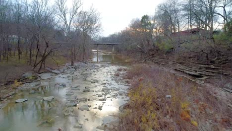 beautiful aerial shot of cedar creek in monterey kentucky at sunset in the fall flying toward a bridge in the distance