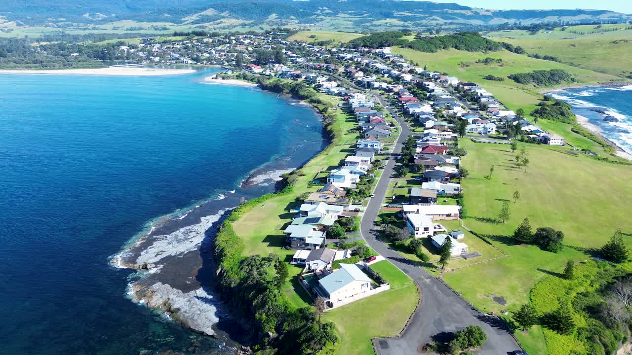 Drone aerial landscape of rural town streets with residential homes along main road headland coastline of Gerroa near the Crooked River inlet in Illawarra South Coast Australia holiday travel outdoors