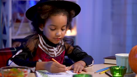 child in halloween costume drawing at a table