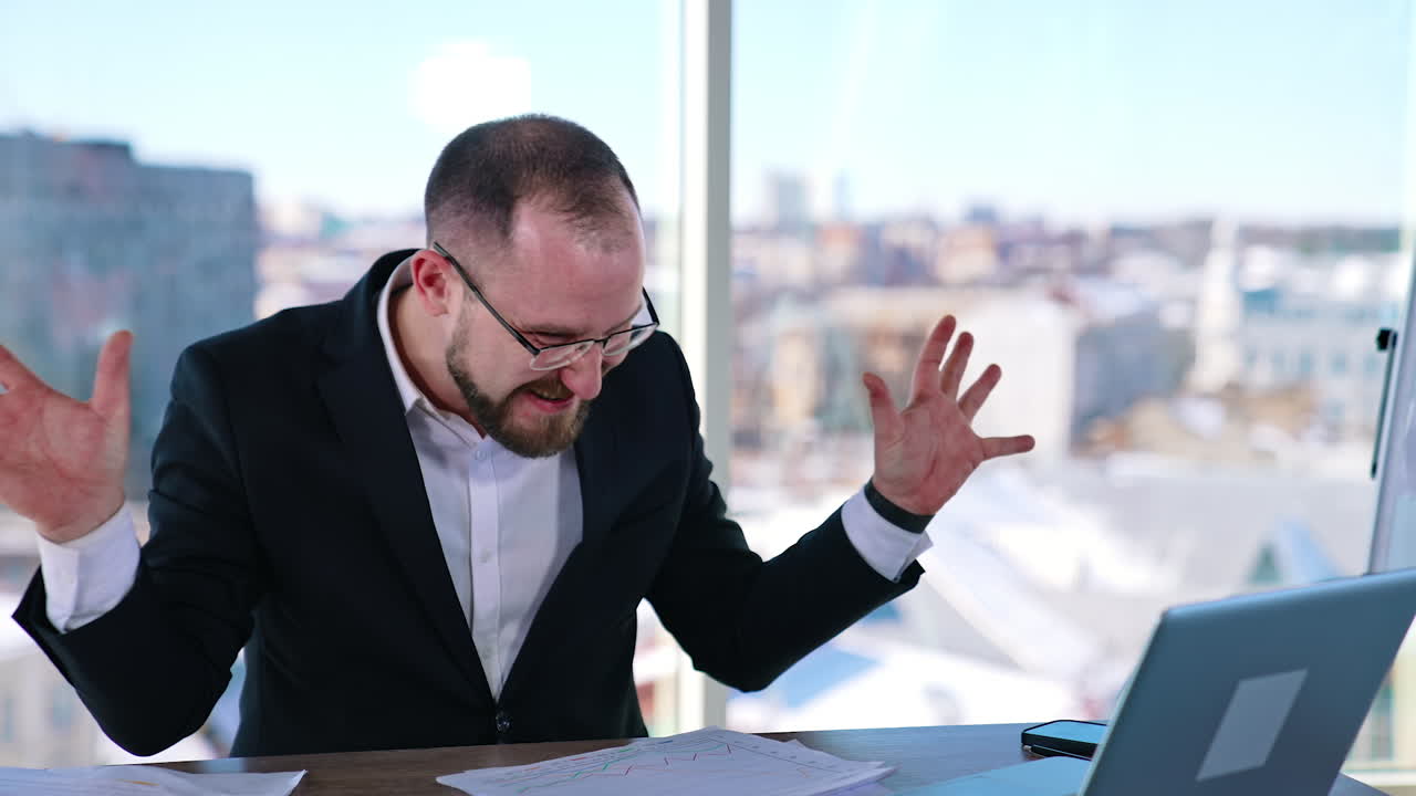 Crazy entrepreneur in office. Out of mind businessman typing quickly on a laptop. Funny man in suit sitting at the table in front of a laptop.