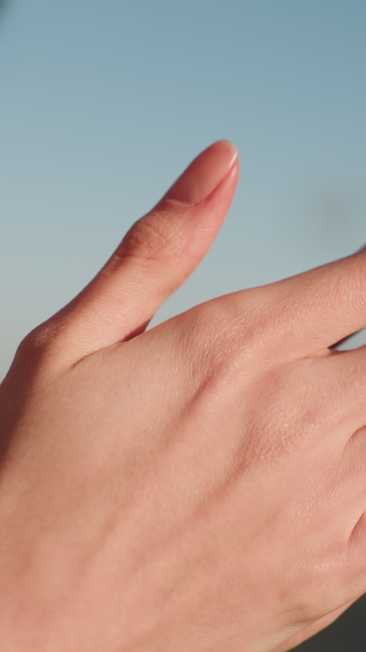 Close-up shot of hands gently rubbing together, conveying a subtle gesture of deep contemplation and grief. The person's head is partially visible, hinting at a moment of sorrow