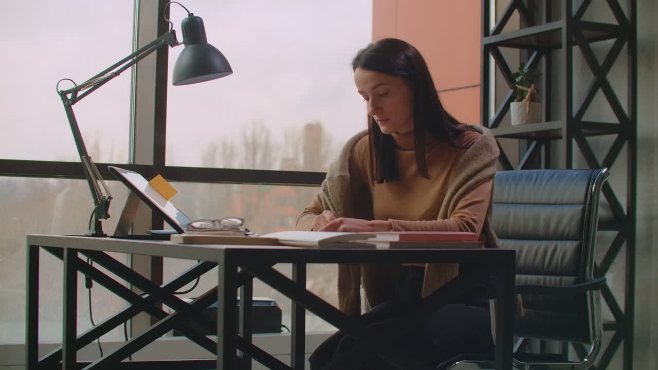 A female graphic designer works in an office with large Windows and paints using a stylus and a computer touch screen. Workstation with touchscreen for designers. Come up with and develop the concept of the logo.