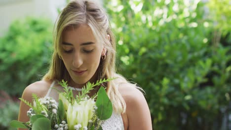 feliz mujer caucásica sosteniendo un ramo de flores en el jardín en un día soleado