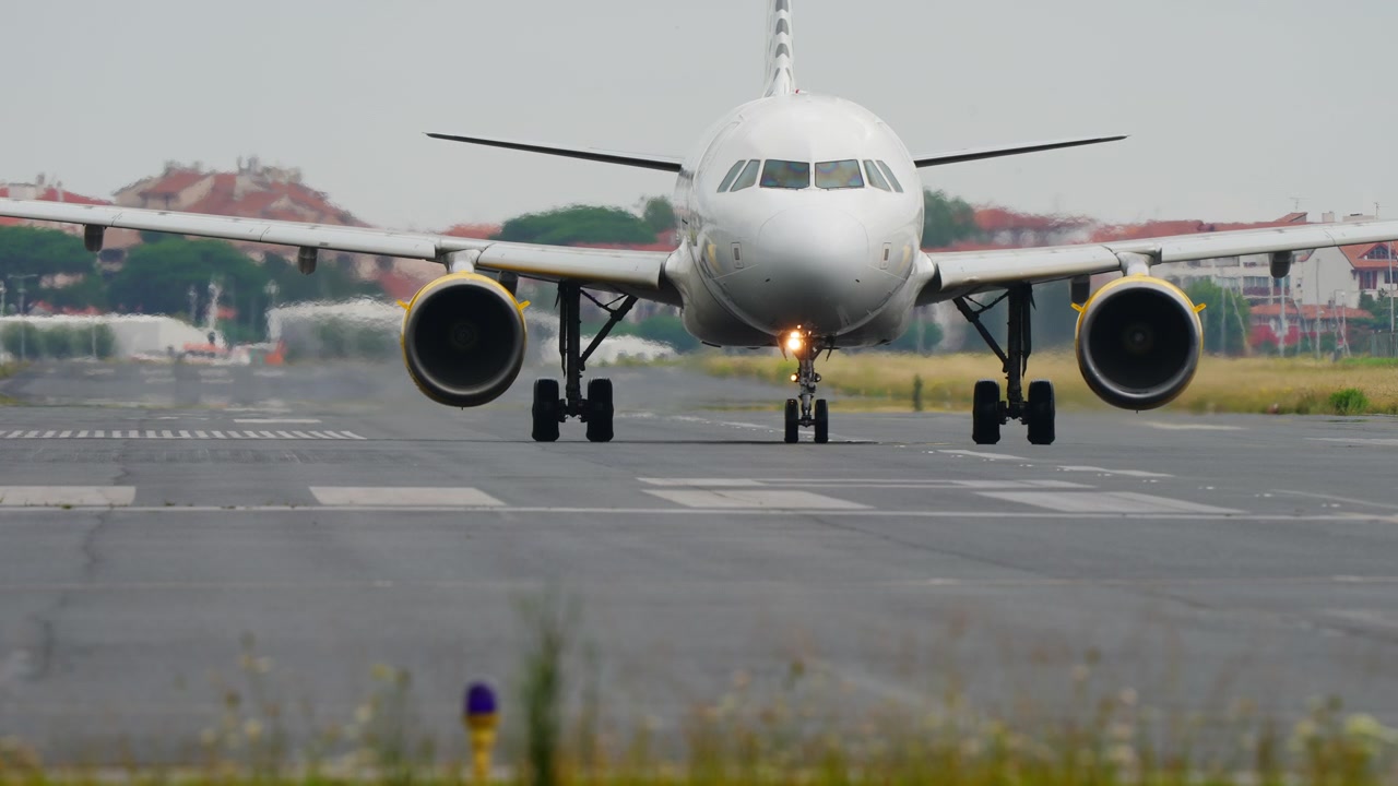 Jet commerciale a fusoliera stretta in rullaggio frontale sulla pista, da angolazione bassa