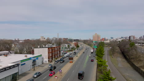 Aerial-view-of-vehicles-driving-on-multilane-road-in-urban-neighbourhood.-Commercial-and-residential-buildings-along-street.-Boston,-USA