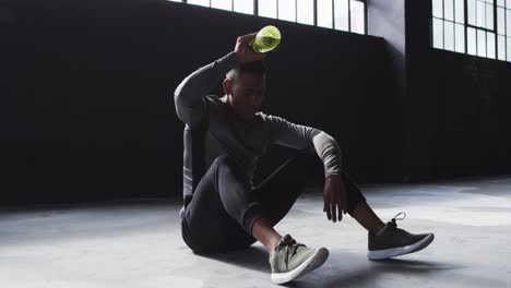 african american man sitting in an empty building pouring water on his head