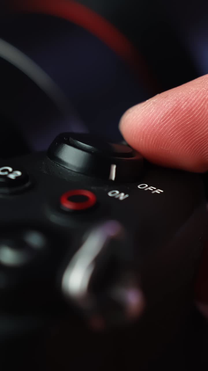Macro of a finger sliding a mirrorless camera power lever to OFF, shutting the device down after filming in a studio. Vertical close-up with shallow depth of field