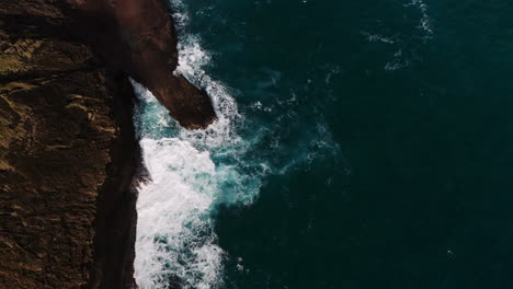 Toma-Aérea-De-Drones-A-Vista-De-Pájaro-De-Olas-Rompiendo-Contra-La-Costa-Rocosa