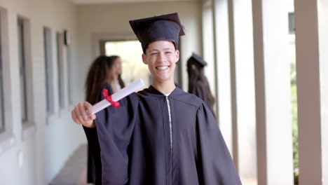 un adolescente biracial orgulloso celebra su graduación en la escuela secundaria