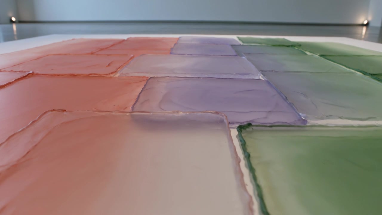 Moving camera following swatches orange purple green forward, upward at studio table, showing edges
