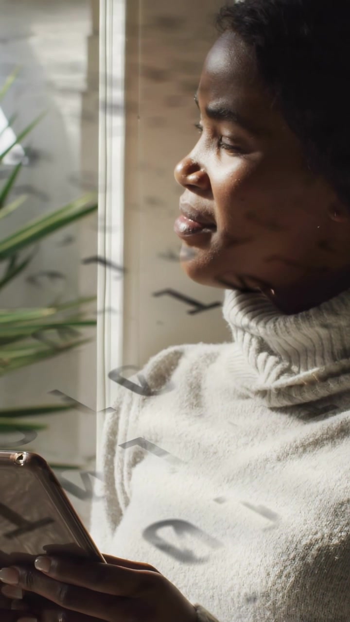 Video verticale: Donna con tablet alla finestra che guarda in basso e poi fuori, con una sovrapposizione tecnologica che si muove sul maglione.