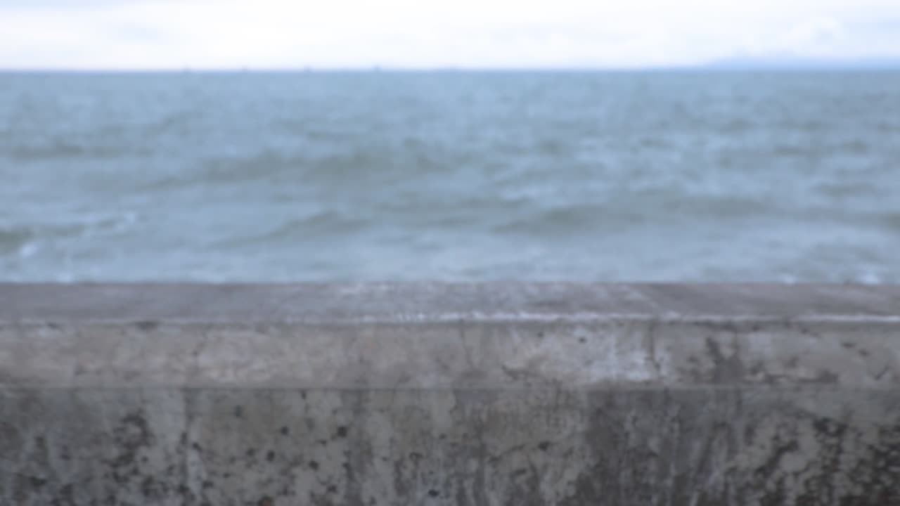 보라색 파도가 큰 바위에 충돌하기 위해 프레임에 들어오면서 카메라가 벽을 뒤로 당깁니다.