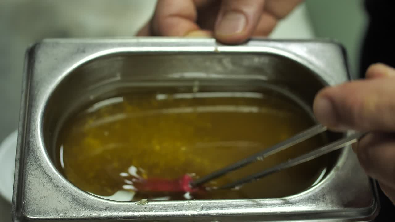 шеф-повар помешивает соус кисточкой в металлической кастрюле, крупный план