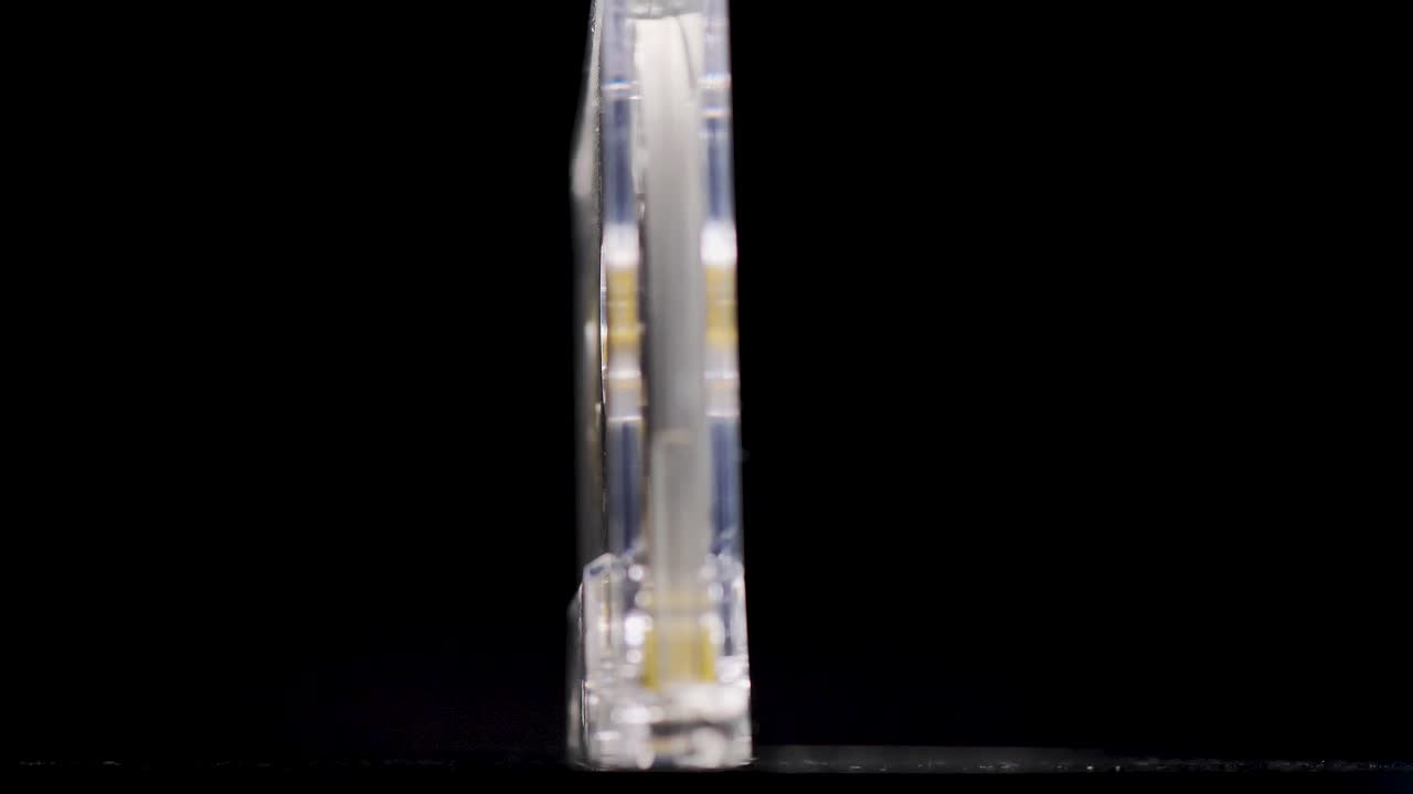 casete de audio transparente amarillo giratorio sobre un fondo negro