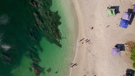 scenic rocky beach shore with tourists on sand at playa conchal, costa rica, 4k drone flyover