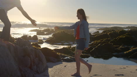 man giving helping hand to woman on beach 4k