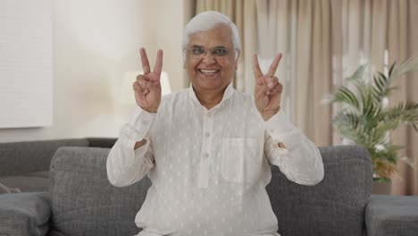 happy indian old man showing victory sign