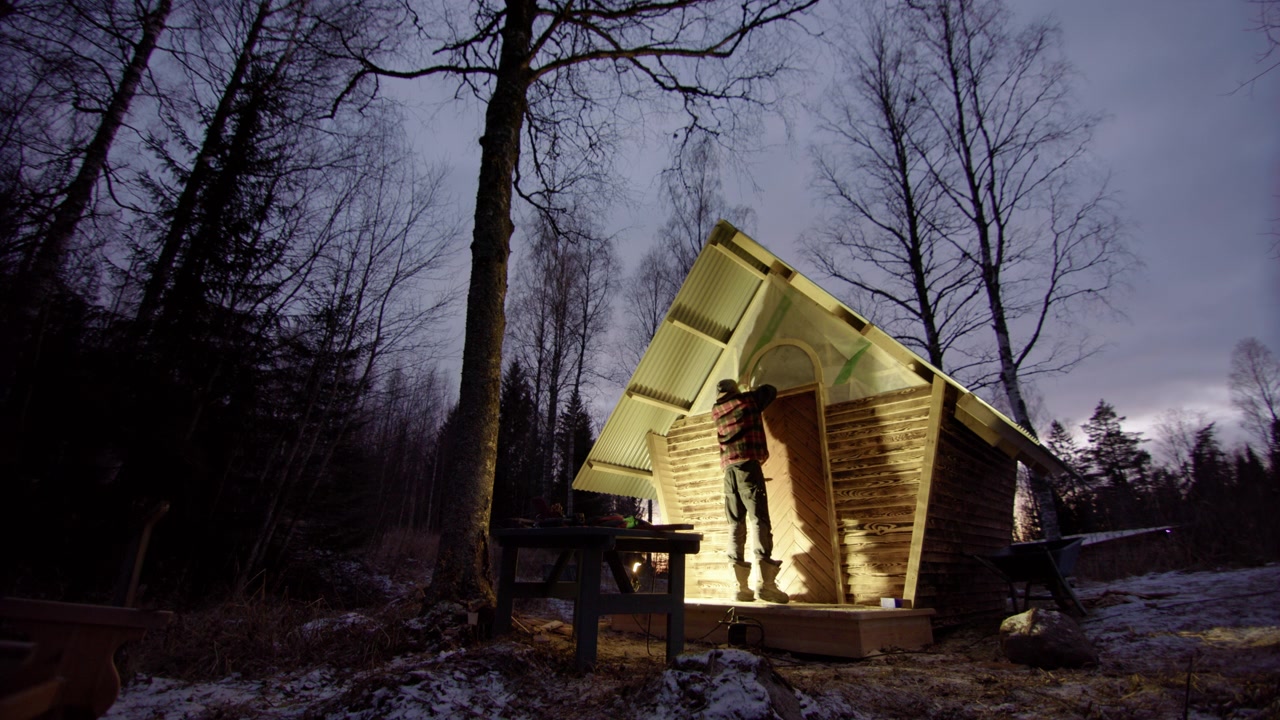 Handyman use frame to mark where new window in wooden cabin will be cut, night