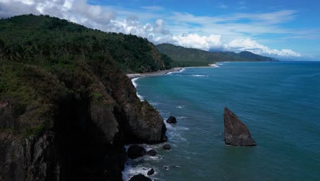 a drone shot captures a small mountain beside the ocean, with waves gently lapping against the shore, creating a serene and scenic coastal landscape that blends rugged terrain with calm waters.