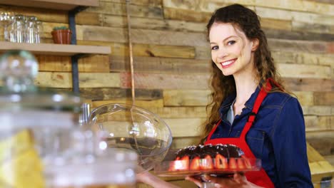 portrait of smiling waitress holding cake at counter