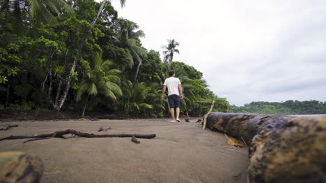 Jóvenes-Viajeros-Mochileros-Caminando-Sobre-Un-Tronco-De-Madera-Palmera-En-Una-Solitaria-Playa-De-Arena-En-El-Paraíso-De-Costa-Rica-Centroamérica