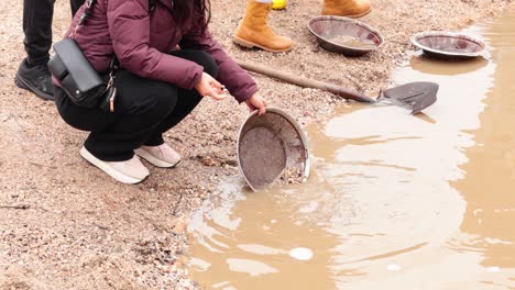 people panning for gold in muddy water