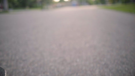 perspectiva de ángulo bajo de obturador alto de longboard mientras recorre una carretera