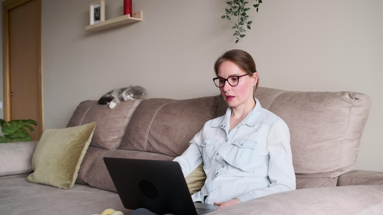 Woman working on laptop at home with cat