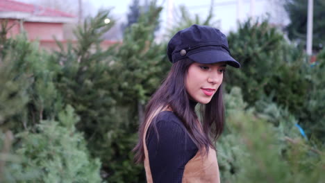 a hispanic woman in the holiday spirit shopping for festive christmas trees