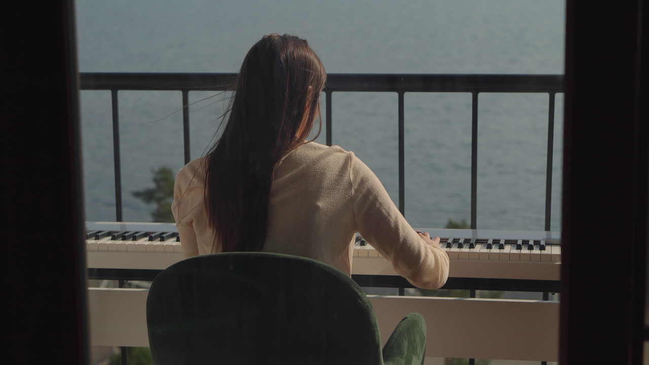 Donna che suona il pianoforte su un balcone con vista sull'oceano