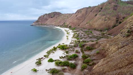 drones aéreos sobrevuelan una playa de arena blanca aislada y remota, vistas costeras y colinas de estación seca en dili, timor leste