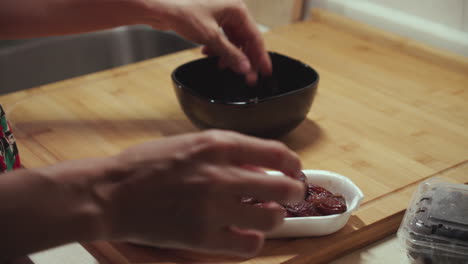 la mujer quita las semillas de la fruta del dátil y las pone en un plato hondo negro