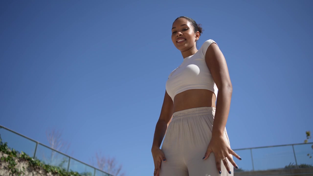 Una donna elegante in abbigliamento sportivo si gode l'aria aperta contro un cielo azzurro limpido.