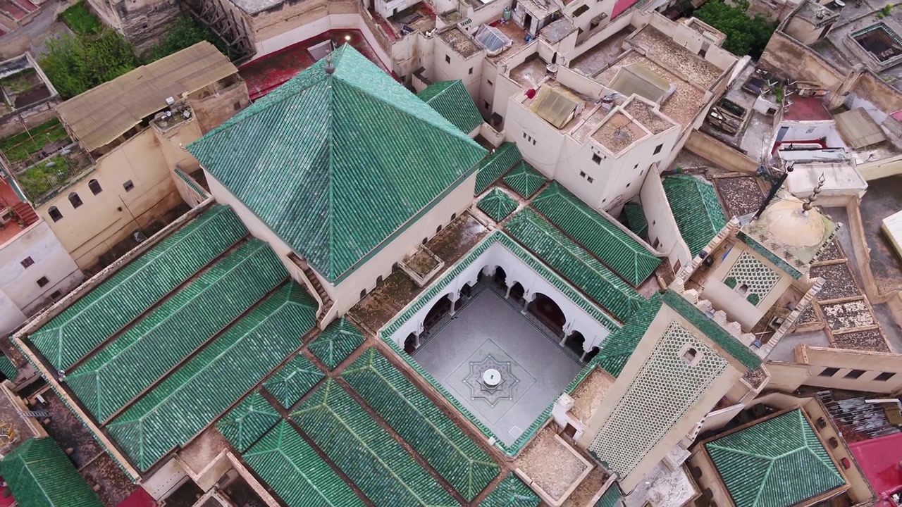 Vista aerea dall'alto con drone dei tetti e del minareto della Moschea Al Quaraouiyine, circondati da fitti edifici storici nella Medina di Fez, Marocco, ideale per progetti culturali e di viaggio.
