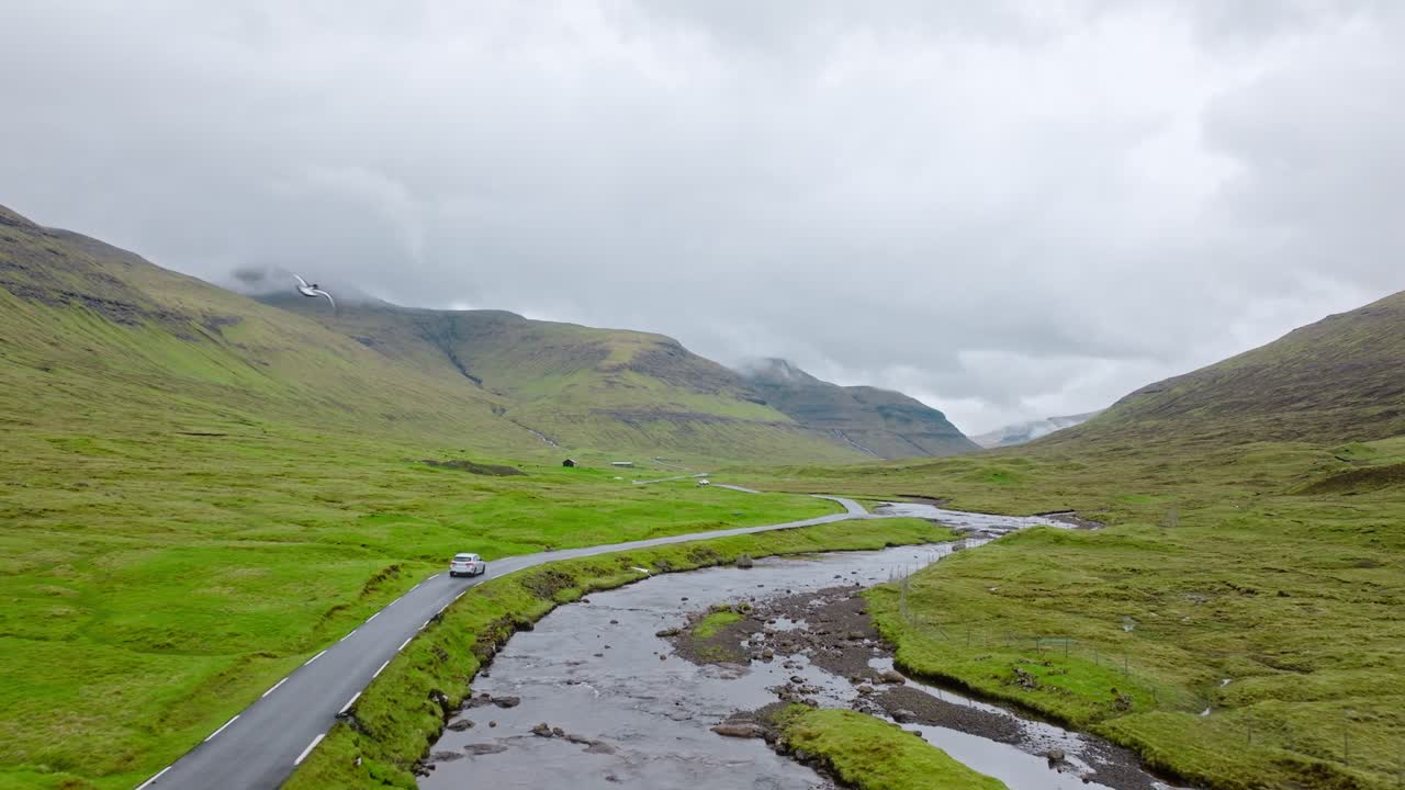 A peaceful green valley in the Faroe Islands with a winding river and a quiet road