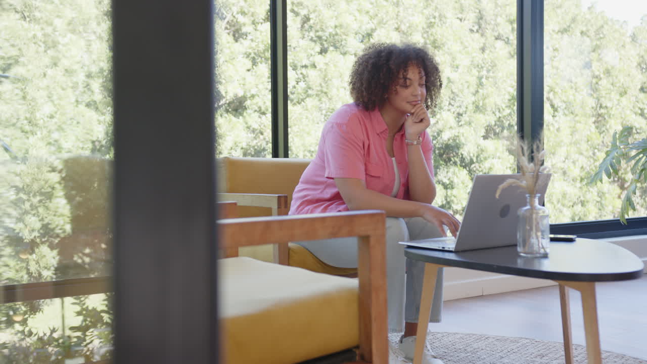 Sitting on chair, woman using laptop and focusing on work in modern room