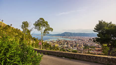 Timelapse-footage-of-a-coastal-city-in-Europe-captured-from-an-elevated-land-with-trees-and-people-moving-along-the-road-Italy-Sicily