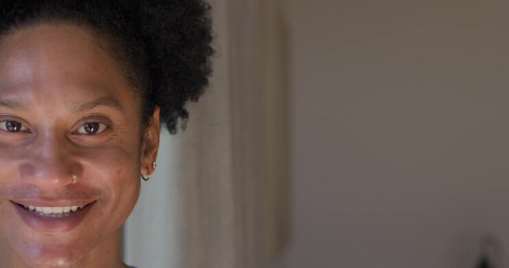 African American woman shifting gaze to camera on cue, smiling near curtain showing nose ring