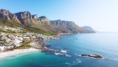 Antenne-Bewegt-Sich-Entlang-Der-Küste-Von-Camps-Bay-Kapstadt-Südafrika-Mit-Zwölf-Apostel-Bergen-Hintergrund