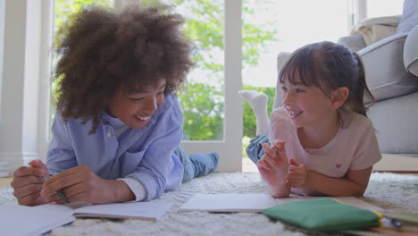 Boy-And-Girl-Lying-On-Rug-In-Lounge-At-Home-Doing-School-Homework-Together