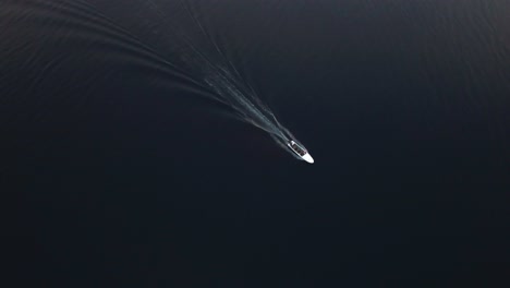 Top-Down-Birdseye-Aerial-View-on-Boat-Sailing-on-Calm-Water-Surface-Under-Sunrise-Sunlight