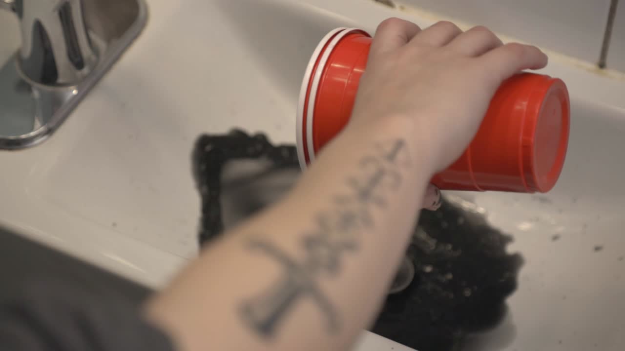 Painter Disposing The Dirty Water From The Red Plastic Cup In The Sink - High-Angle Shot
